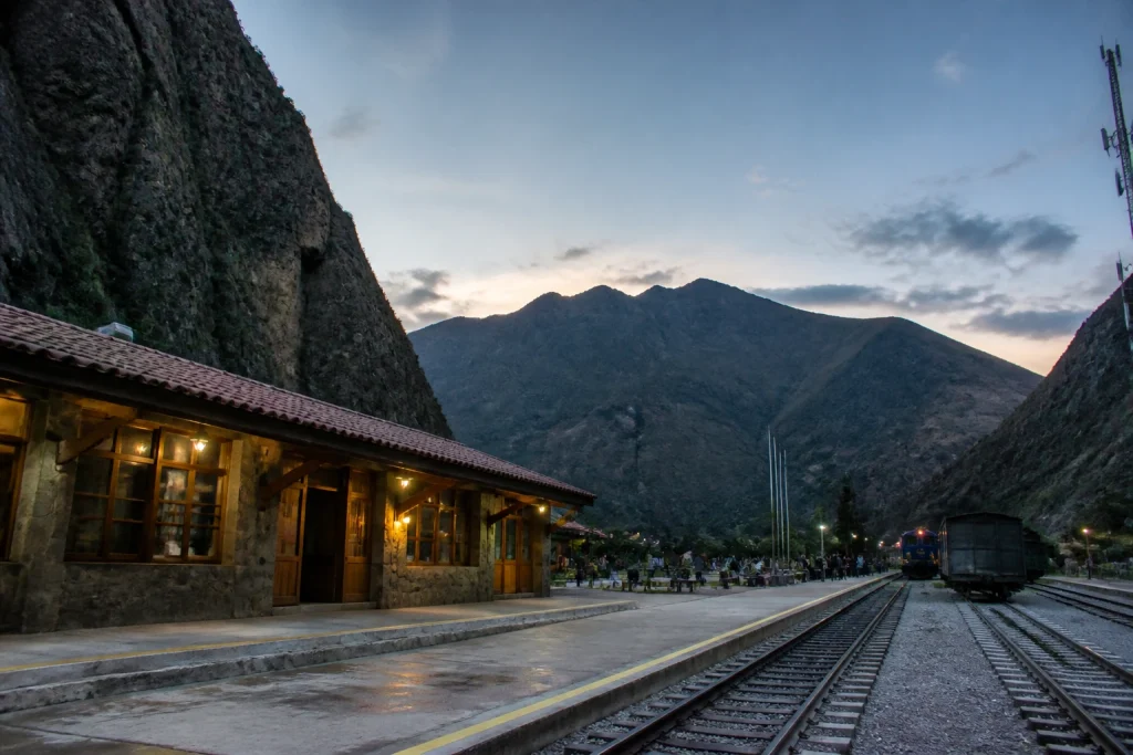 Rail infrastructure at Ollantaytambo railway station with Andean mountains behind it.