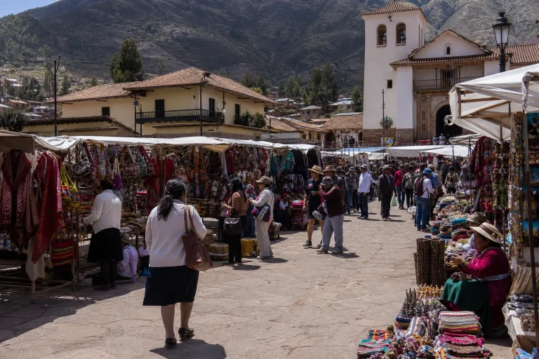 Market stalls and shoppers in Plaza Constitución in Pisac