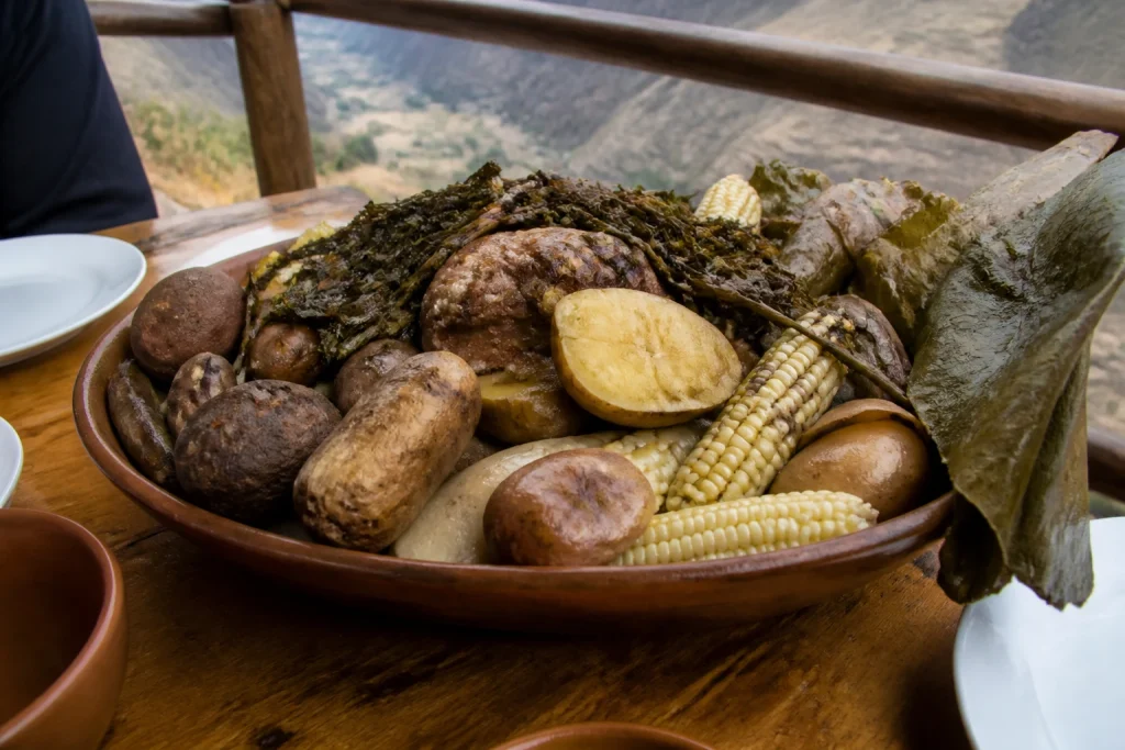 Pachamanca with potatoes, corn, herbs, and assorted ingredients